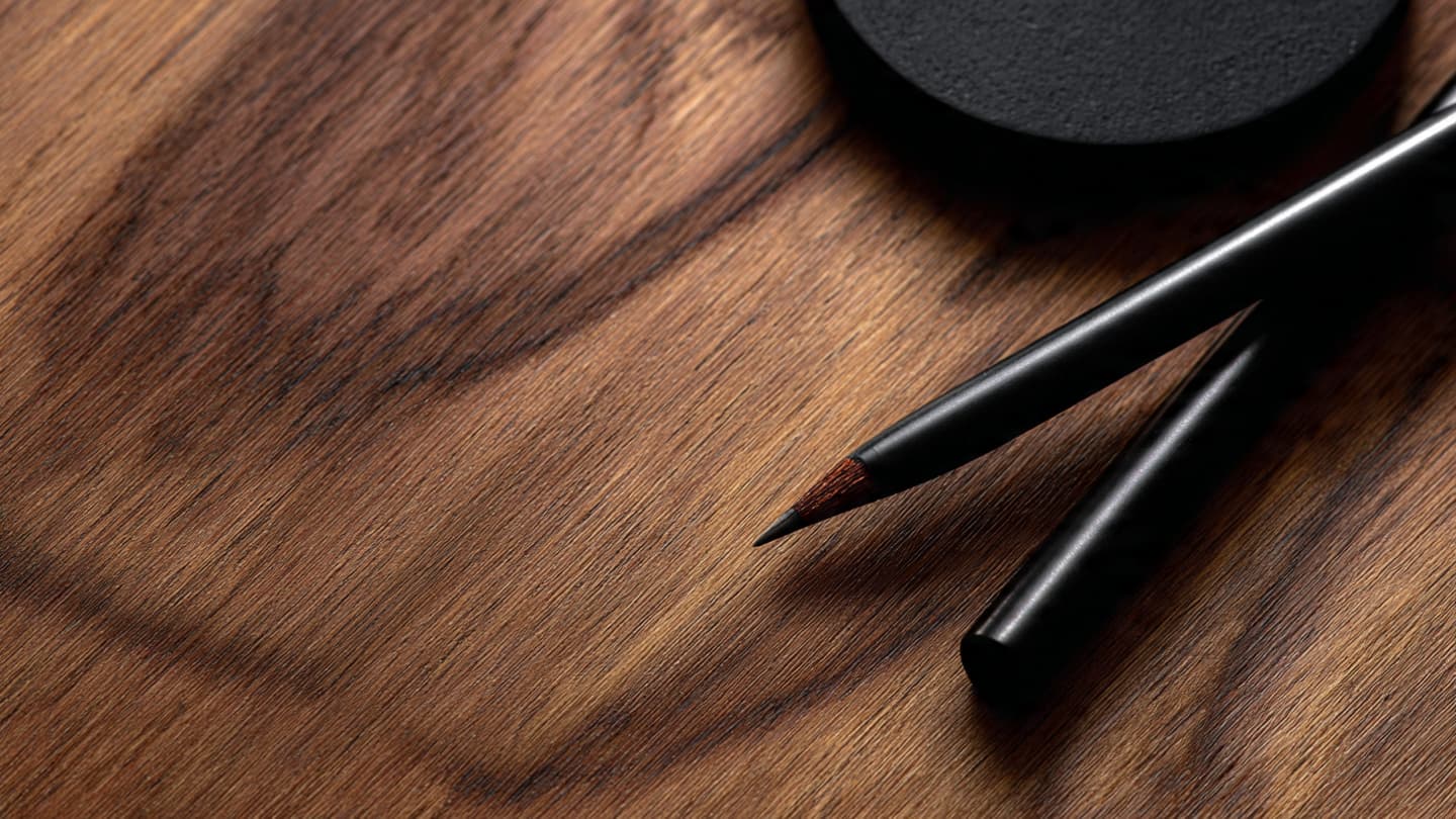 Close-up of walnut texture and matte black desk accessories